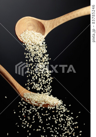 Grains of sesame are poured with wooden spoons. Grains of sesame are poured with wooden spoons. 83785246