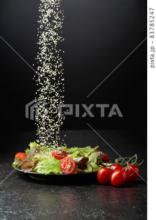 Green salad with tomatoes cherry is sprinkled with sesame seeds. Green salad with tomatoes cherry is sprinkled with sesame seeds. 83785247