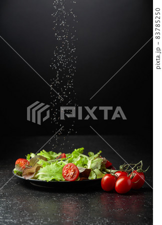 Green salad with tomatoes cherry is sprinkled with sesame seeds. Green salad with tomatoes cherry is sprinkled with sesame seeds. 83785250