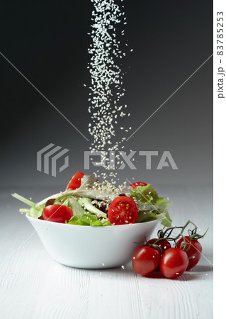 Green salad with tomatoes cherry is sprinkled with sesame seeds. Green salad with tomatoes cherry is sprinkled with sesame seeds. 83785253