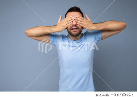 Photo of adult handsome brunet unshaven man with beard with sincere emotions wearing casual blue t Photo of adult handsome brunet unshaven man with beard with sincere emotions wearing casual blue t 83785617