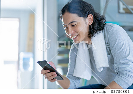 建築現場でスマホを片手に休憩する若い男性 83786301