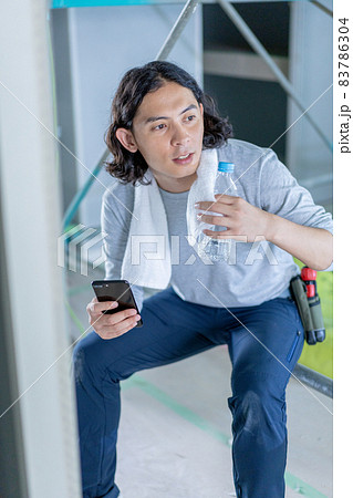 建築現場でスマホを片手に休憩する若い男性 建築現場でスマホを片手に休憩する若い男性 83786304