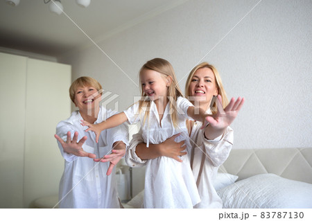 family portrait: mom, daughter and granddaughter are sitting on the bed family portrait: mom, daughter and granddaughter are sitting on the bed 83787130