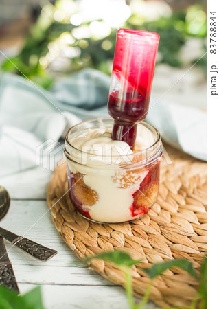 Layered dessert with fruits, nuts and cream cheese in glass jar, selective focus. Layered dessert with fruits, nuts and cream cheese in glass jar, selective focus. 83788844