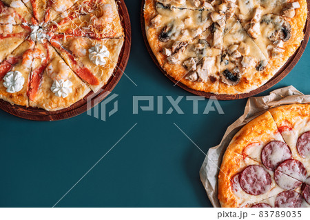 Three pizzas with different toppings on cyan background Three pizzas with different toppings on cyan background 83789035