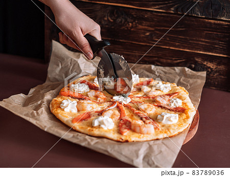 Cutting fish and shrimp pizza into equal pieces with special knife 83789036