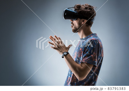 Side view of a young guy using a VR headset. Emotions 83791383