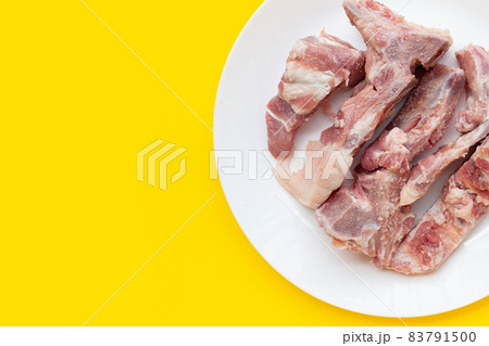 Raw pork bone in white plate on background. Raw pork bone in white plate on background. 83791500