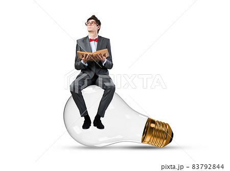 A young businessman sits on a light bulb 83792844