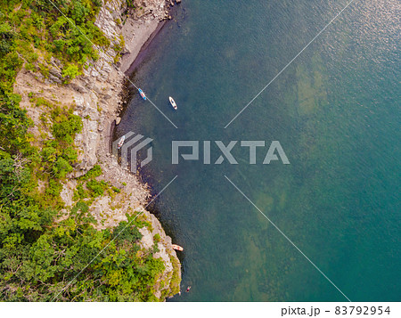 Young women Having Fun Stand Up Paddling in the sea. SUP. Red hair girl Training on Paddle Board near the rocks Young women Having Fun Stand Up Paddling in the sea. SUP. Red hair girl Training on Paddle Board near the rocks 83792954