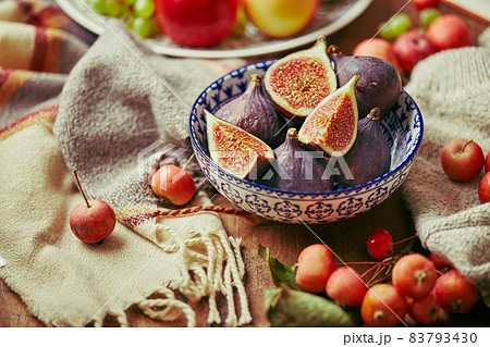 Dish with figs, apples and grapes with warm cozy knitwear, autumn leaves and apples. 83793430