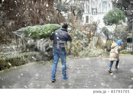 Father bought a Christmas tree and is carrying it home Father bought a Christmas tree and is carrying it home 83793705