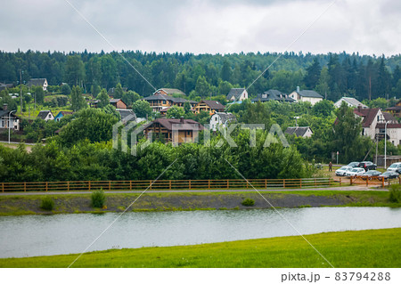 View from a height of cottages by the river. A view from above on a panorama of cottages by the river. Mountain landscape 83794288