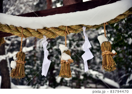 山間部の神社の大きなしめ縄に雪が積もっている 83794470