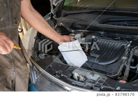 Auto mechanic wipes the dipstick to check the oil level in the engine. Auto mechanic wipes the dipstick to check the oil level in the engine. 83796570