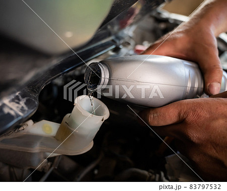 An auto mechanic pours brake fluid into the car An auto mechanic pours brake fluid into the car 83797532