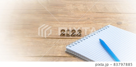Notebook and pen on the table. A blank sheet of paper and a ballpoint pen. Wooden numbers 2022. Notebook and pen on the table. A blank sheet of paper and a ballpoint pen. Wooden numbers 2022. 83797885