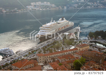 Stone houses with shingles against the background of a cruise liner. Evening in Bokokotorska Bay. The concept of tourism in Montenegro 83797929