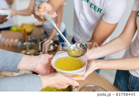 Volunteers serving hot soup for homeless in community charity donation center, group of young people helping with food Volunteers serving hot soup for homeless in community charity donation center, group of young people helping with food 83798445