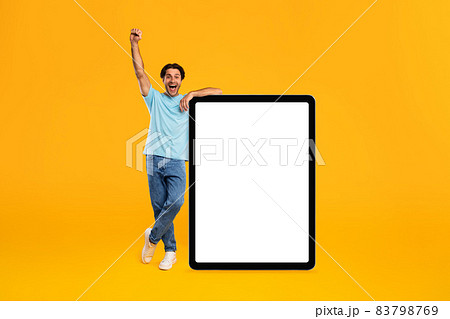 Yes. Man leaning on blank empty tablet screen celebrating success 83798769