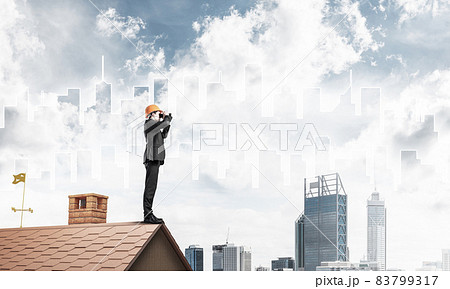 Engineer man standing on roof and looking in binoculars. Mixed m Engineer man standing on roof and looking in binoculars. Mixed m 83799317