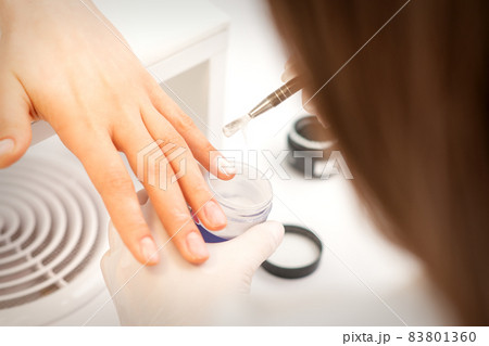 Manicure master applying acrylic powder on the female nails in a beauty salon. Strengthening of nails acrylic powder. Manicure master applying acrylic powder on the female nails in a beauty salon. Strengthening of nails acrylic powder. 83801360