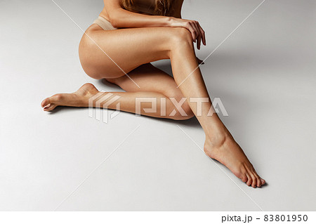 Close-up female tanned body, legs isolated over gray studio background. Natural beauty, spa, anti-cellulite concept. Close-up female tanned body, legs isolated over gray studio background. Natural beauty, spa, anti-cellulite concept. 83801950