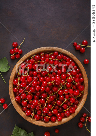 Fresh red currant in wooden bowl on dark table Fresh red currant in wooden bowl on dark table 83806341