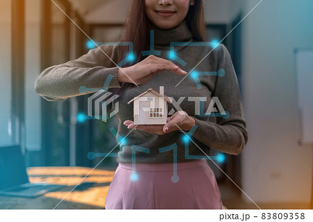 A real estate agent demonstrates the House model to clients interested in purchasing house insurance. The concept of home insurance and property. A real estate agent demonstrates the House model to clients interested in purchasing house insurance. The concept of home insurance and property. 83809358
