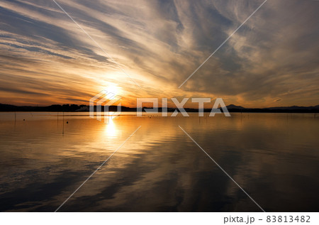 涸沼の夕景。水面に写るオレンジ色の太陽と雲が反射して綺麗、雲の下には筑波山のシルエットが見える 83813482
