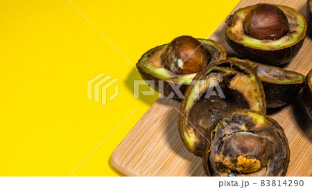 Rotten Avocado on Yellow background. Close up details Rotten tropical Fruits on bambus Chipper. Copy space. Yellow background contains Unhealthy Food. 83814290