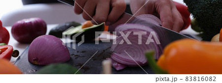 Woman cuts red onion into wedges closeup Woman cuts red onion into wedges closeup 83816082