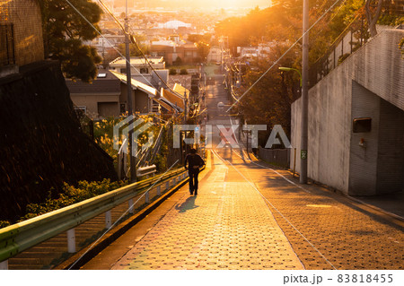 夕陽に照らされ金色に輝く坂道を駆ける人 83818455