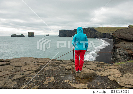 Tourist admiring Dyrholaey peninsula and Atlantic ocean, Iceland Tourist admiring Dyrholaey peninsula and Atlantic ocean, Iceland 83818535