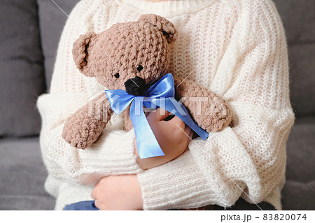 little girl hugging knit teddy bear with blue ribbon. knitting toys for kids, christmas gift. children favorite toy friend 83820074