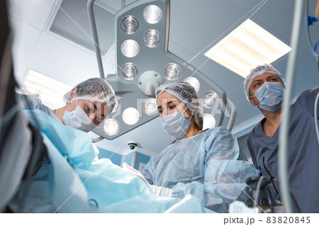 Concentrated Surgical team operating a patient in an operation theater. Well-trained anesthesiologist with years of training with complex machines follows the patient throughout the surgery 83820845