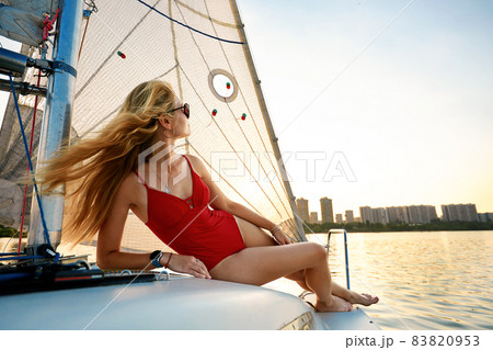 Young beautiful woman in fashion red swimsuit standing on yacht in open sea or ocean, sailing 83820953