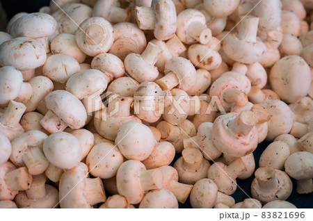 A close-up of champignons. Top view of a shelf with mushrooms in the market. 83821696