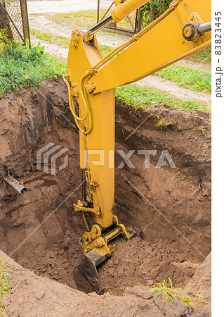 Hydraulic excavator piston digs deep pit in industrial area on construction site 83823445