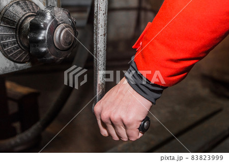 The hand of a working man holds the handle and controls the work of the milling machine The hand of a working man holds the handle and controls the work of the milling machine 83823999