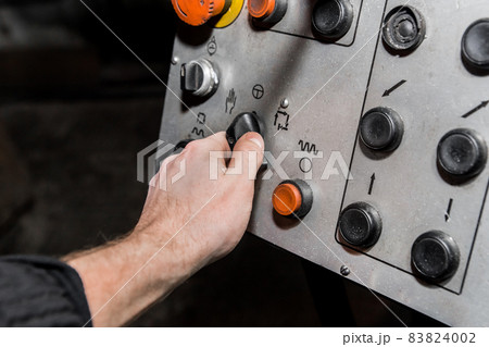 Human hand uses old control panel of industrial equipment in the factory Human hand uses old control panel of industrial equipment in the factory 83824002