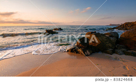 huge stones on the sandy beach at sunrise. wonderful velvet season vacation on the black sea in morning light. calm waves washing the shore of bulgaria. glowing clouds on the blue sky above horizon 83824668