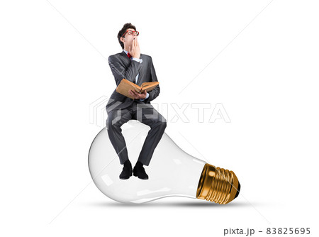 A young businessman sits on a light bulb A young businessman sits on a light bulb 83825695