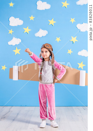Girl pilot playing with toy jet pack at home. Success and leader concept Girl pilot playing with toy jet pack at home. Success and leader concept 83826011