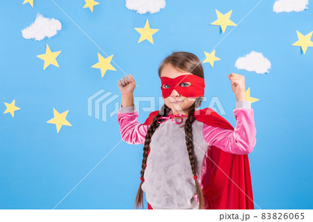 Six year blonde girl dressed like superhero having fun at home. Kid on the background of bright blue wall. Six year blonde girl dressed like superhero having fun at home. Kid on the background of bright blue wall. 83826065