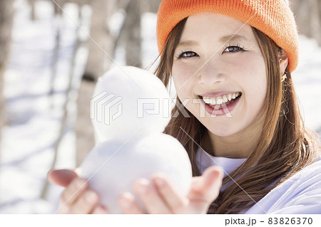 スキー場で小さい雪だるまを作って見せる若い女性　スキースノーボードイメージ　 83826370