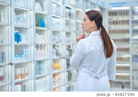 Back view of woman in white coat in pharmacy Back view of woman in white coat in pharmacy 83827390