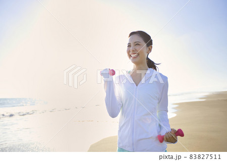 砂浜でウオーキングをするスポーツウエアの若い女性 83827511