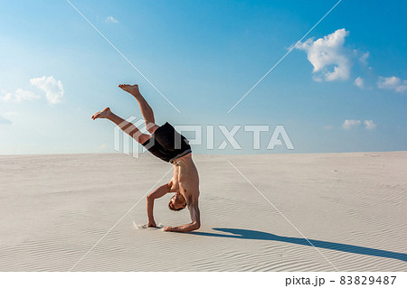 Young man jumping on the beach with white sand and bright blue sky Young man jumping on the beach with white sand and bright blue sky 83829487